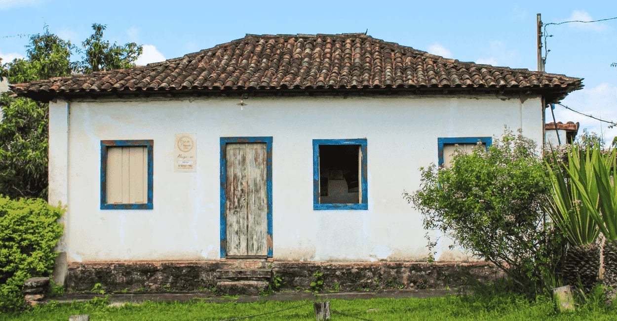 Casa antiga em Chapada, distrito de Ouro Preto, com fachada branca, detalhes azuis e telhado colonia