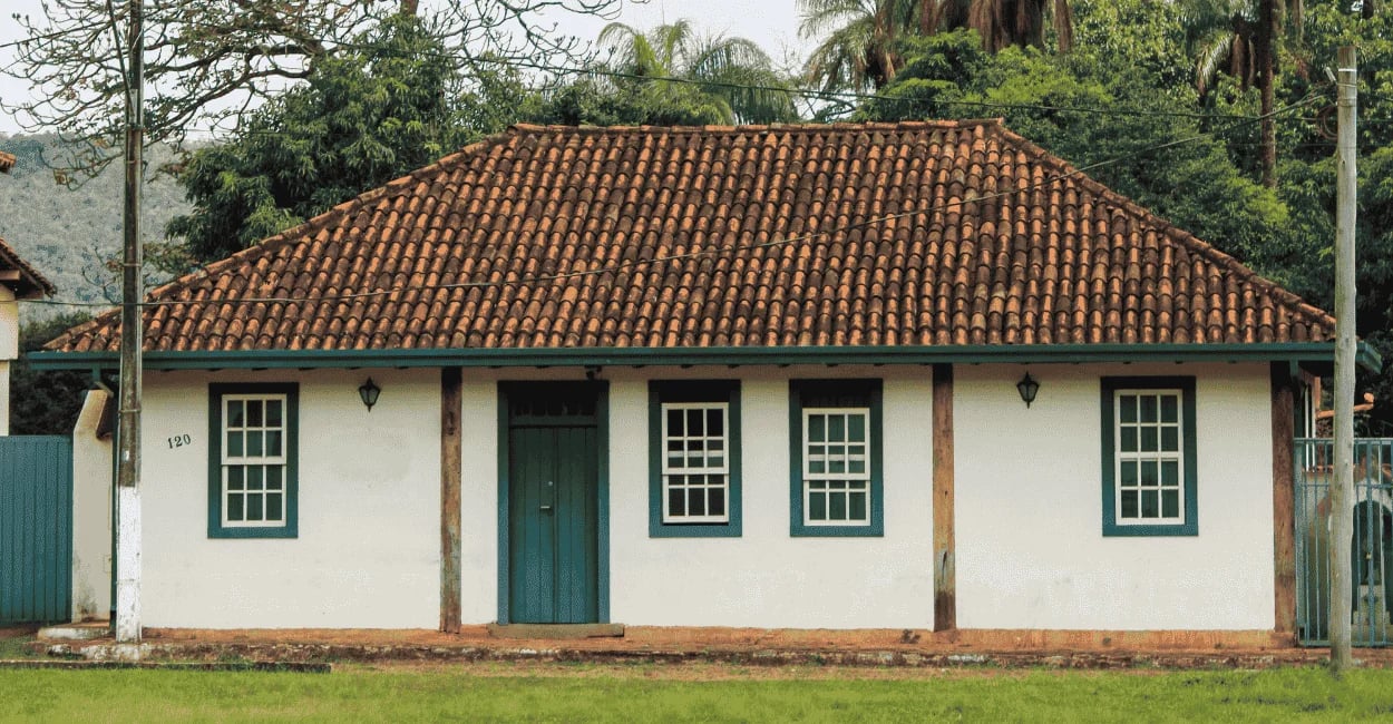 Casa histórica em Brumal MG com fachada colonial, portas verdes e telhado de barro