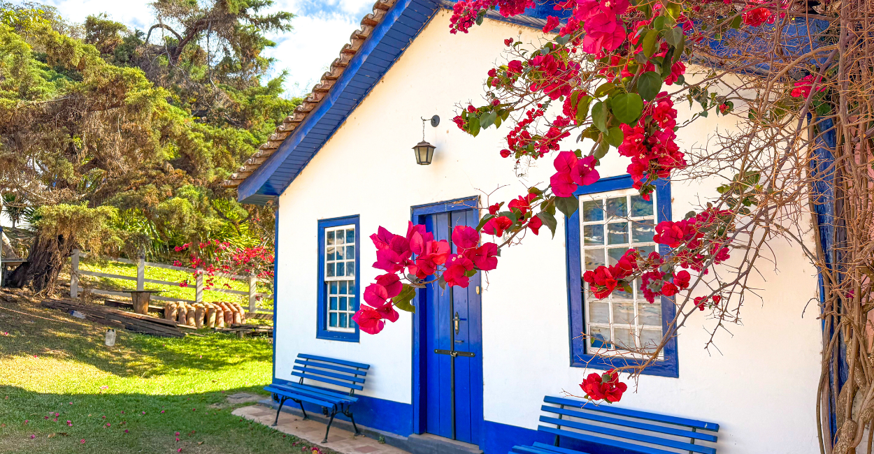 Casa histórica de cor azul e branco com uma árvore com flores na frente, na Vila do Biribiri em MG