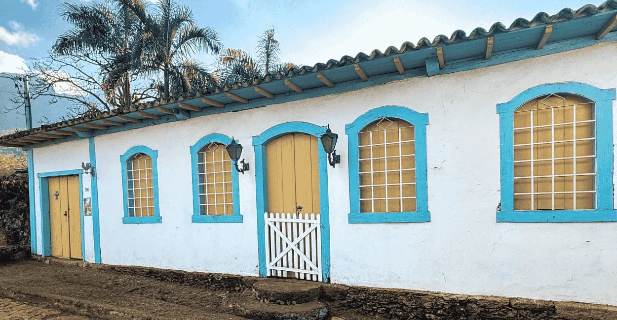 Casarão colonial preservado com janelas azuis e portas amarelas em Morro d’Água Quente MG