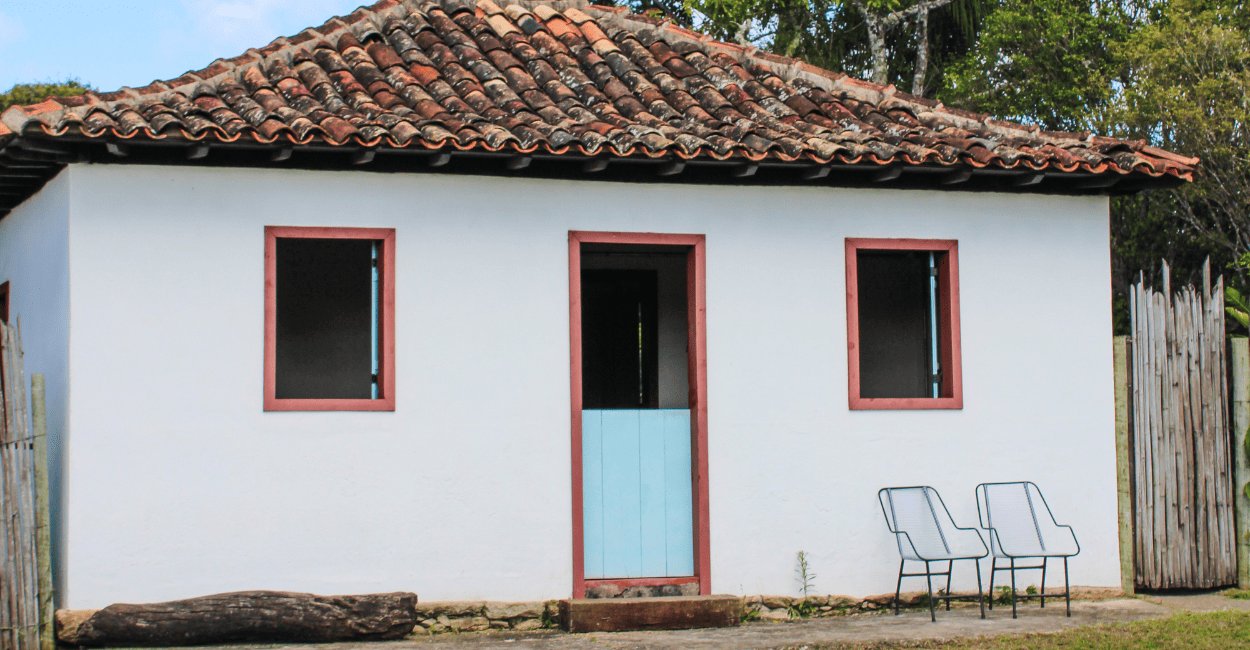 Casa histórica com duas cadeiras a frente, duas janelas e uma porta, em Chapada distrito Ouro Preto