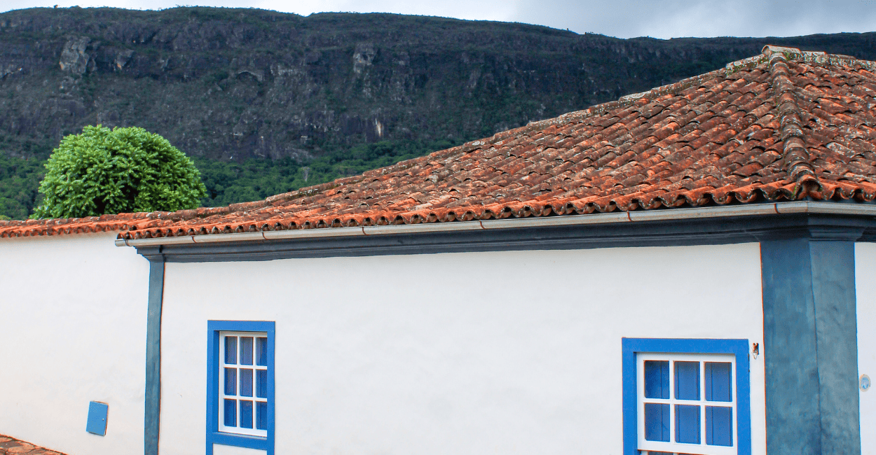 Casa do periodo colonial com cores e telhado bem cuidado e montanha ao fundo, em tiradentes mg