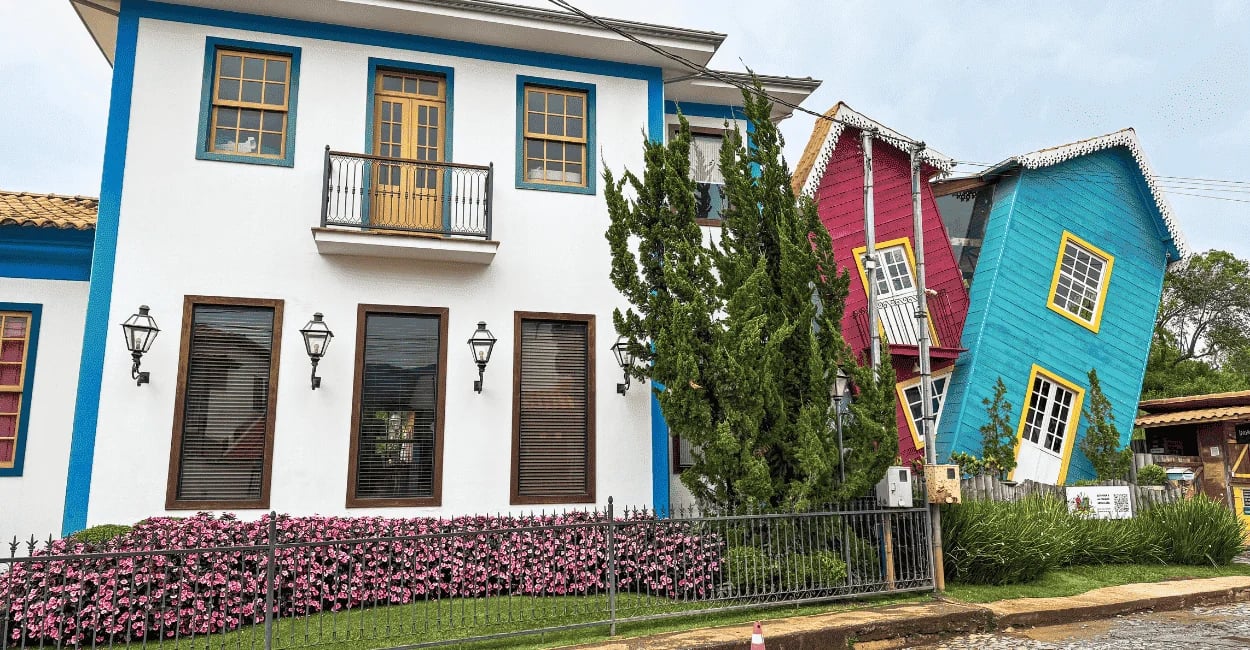 Casa colorida em Bichinho, MG, com estrutura inclinada, fachada azul e rosa e detalhes amarelos