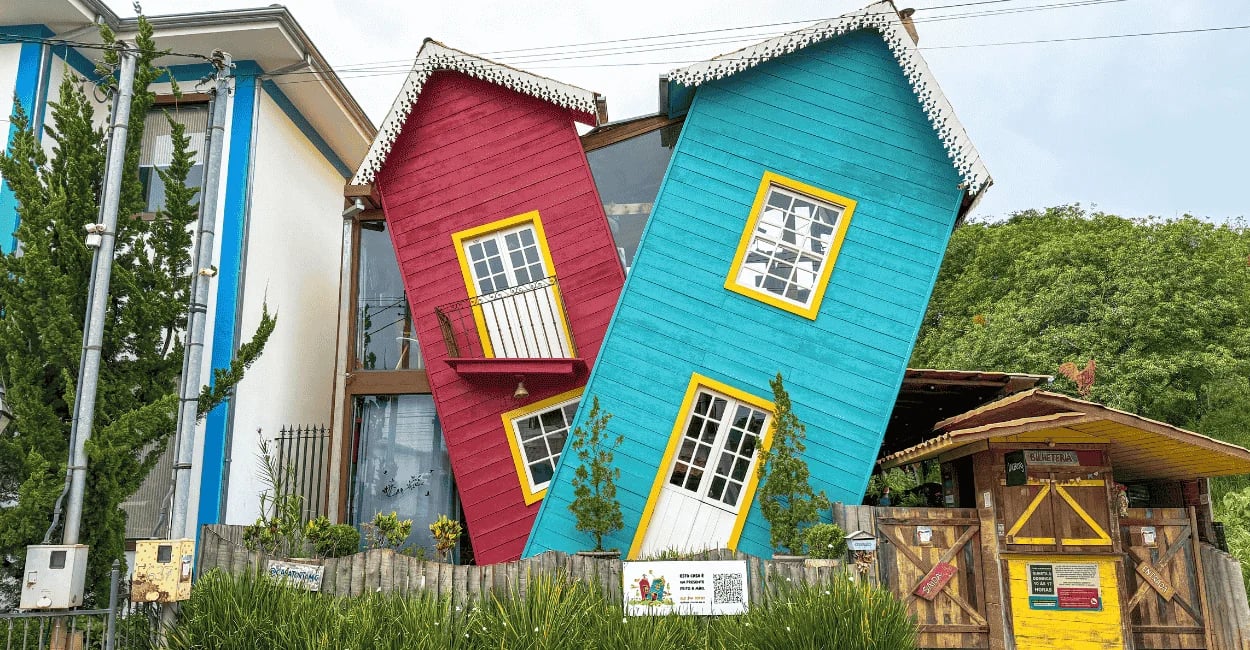 Casa torta, colorida em Bichinho, com fachadas azul e vermelha, janelas amarelas e visual criativo