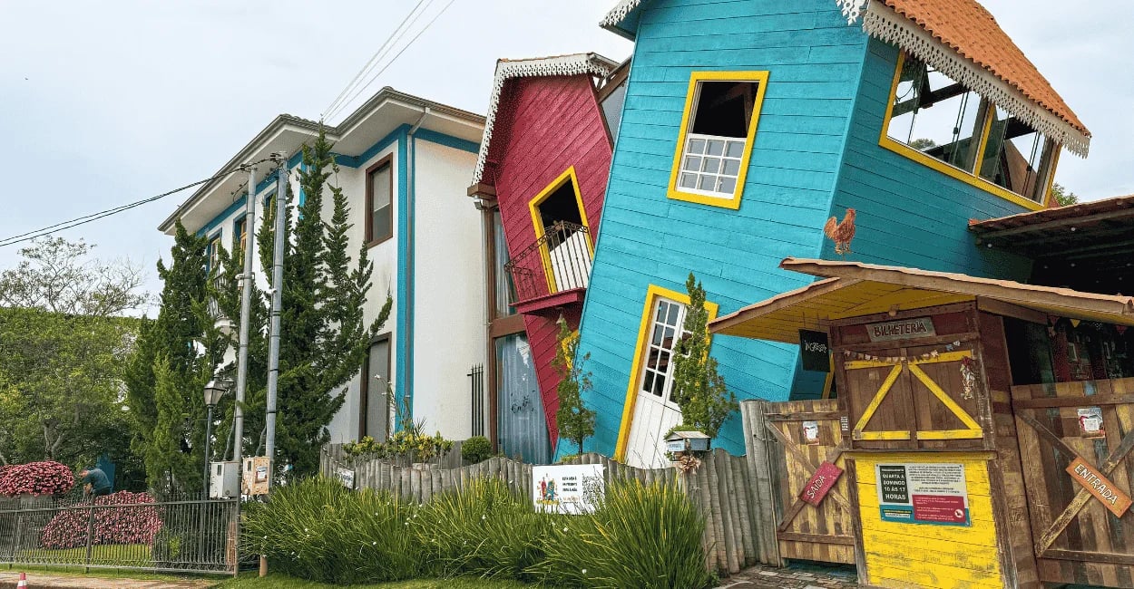 Casa Torta de Bichinho MG com construções inclinadas, cores vibrantes, jardins e entrada turística