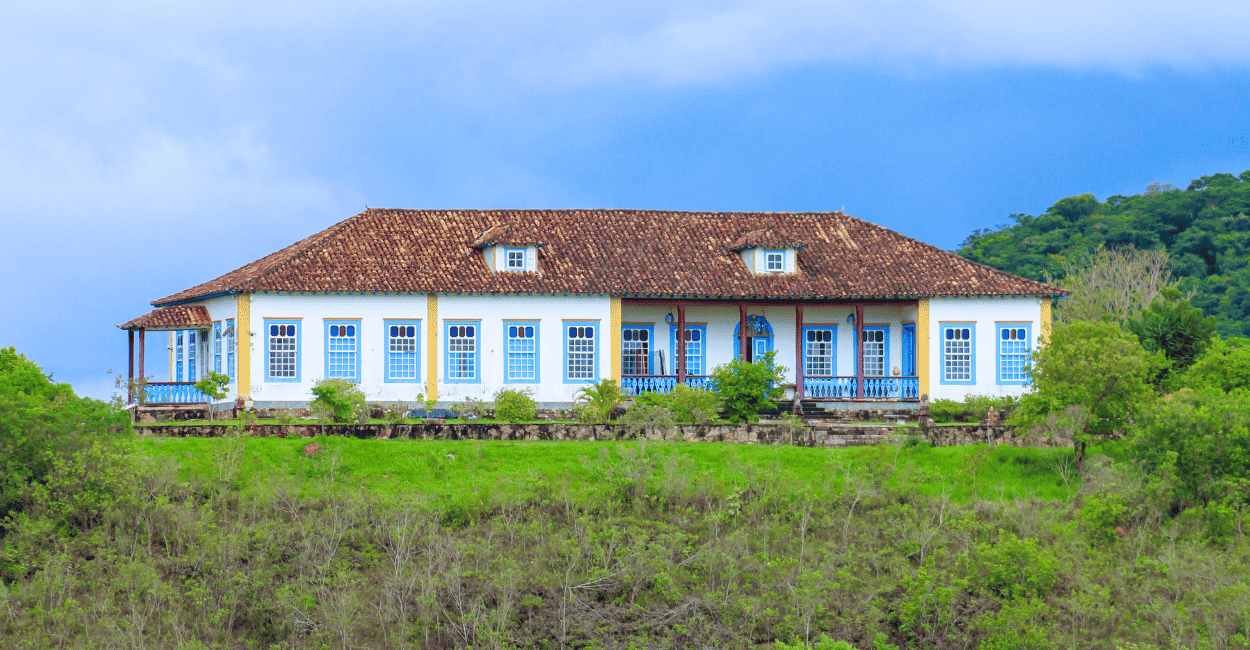Casarão de Fazenda com janelas azuis, pilares amarelos e ceu nublado em Tiradentes MG