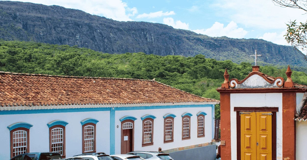 Casario histórico de Tiradentes MG com capela colonial, telhados de barro e serra ao fundo
