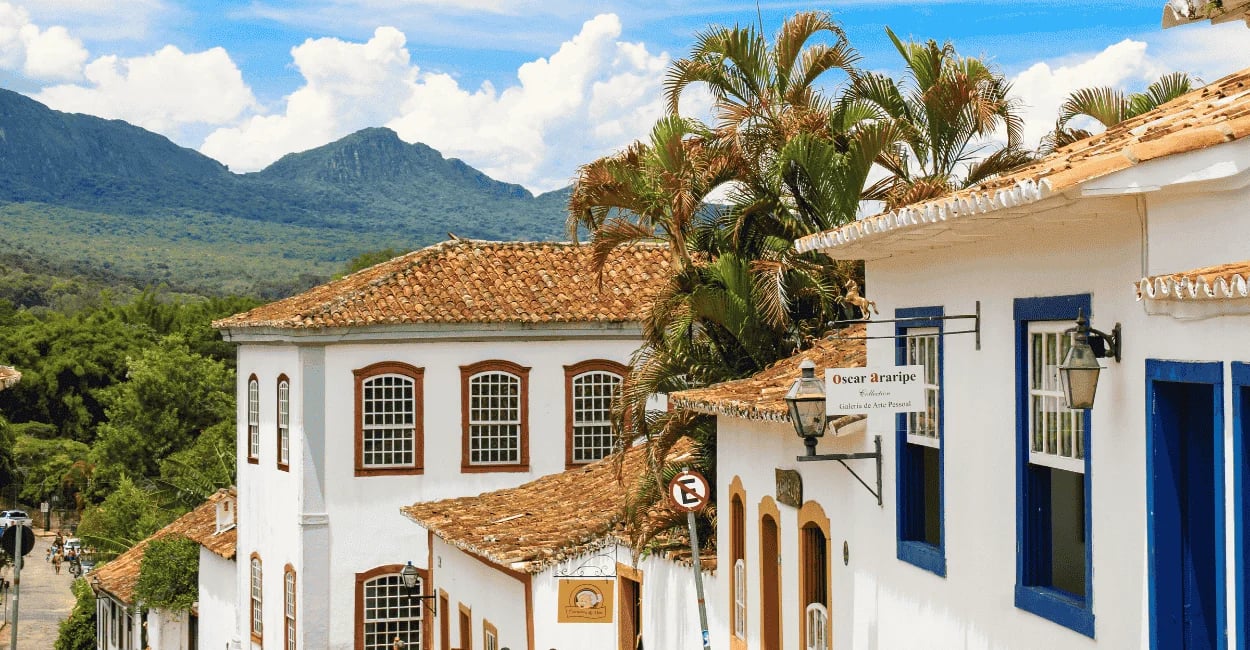 Casarões coloniais brancos com janelas coloridas em rua histórica de Tiradentes com a Serra