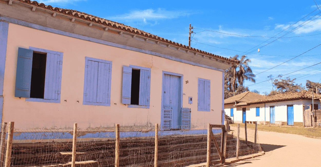 Casas do periodo colonial, com janelas e porta coloridas, céu azul e estrada de terra em Milho Verde