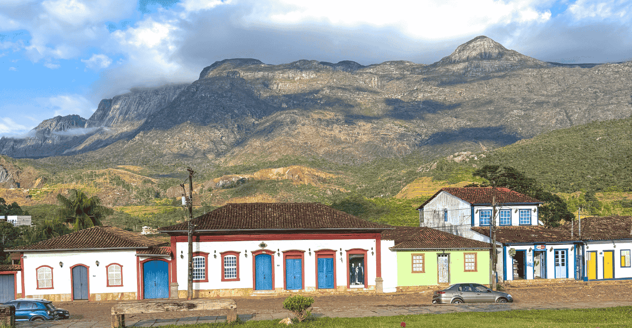 Casas históricas com cores brancas predominantes, com a Serra do Caraça ao fundo, em Catas Altas
