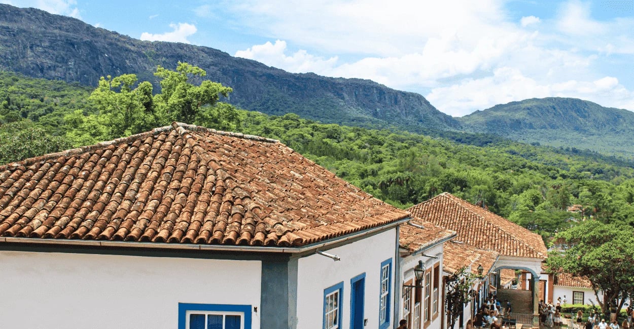 Vista de Tiradentes, MG, com casarões coloniais, telhados de barro e montanhas ao fundo