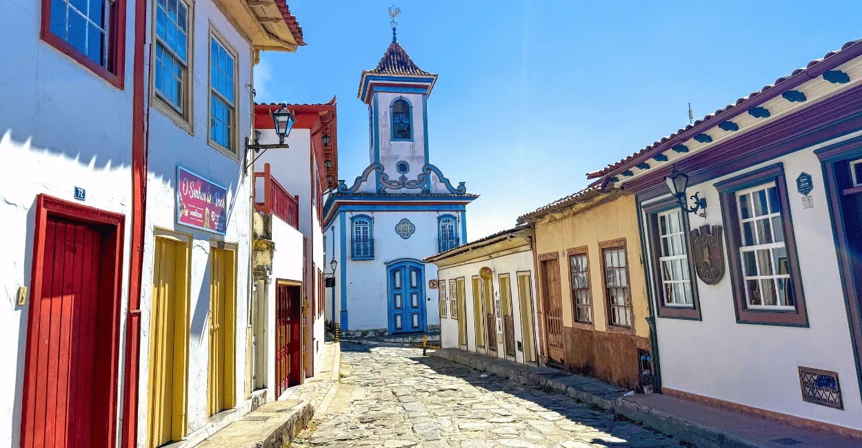 Rua de pedra no centro histórico de Diamantina com casas coloniais e igreja ao fundo