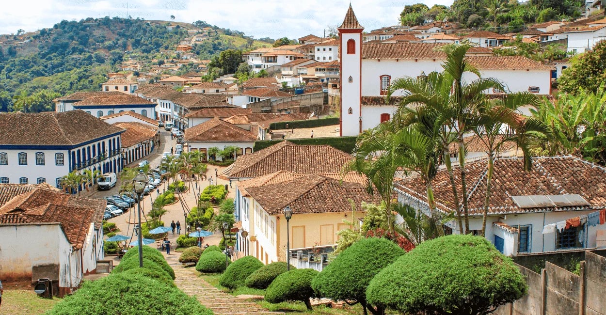 Vista panorâmica do Serro MG com casario colonial, telhados históricos, igreja e jardins no centro