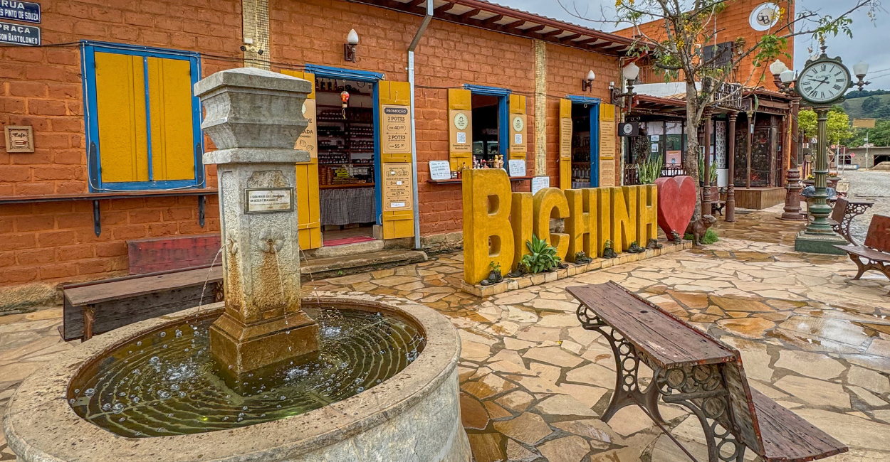 Uma fonte de água com o letreiro de Bichinho com um ocração na letra O no distrito de Bichinho