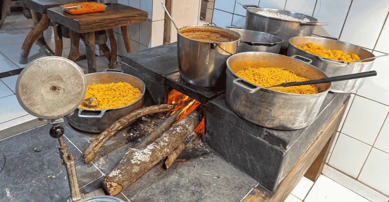 Fogão a lenha em Milho Verde com panelas cheias de comida caseira, fogo aceso