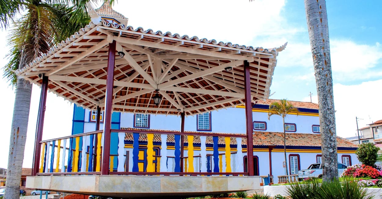 Coreto colorido na praça central de Datas, Minas Gerais, com igreja ao fundo