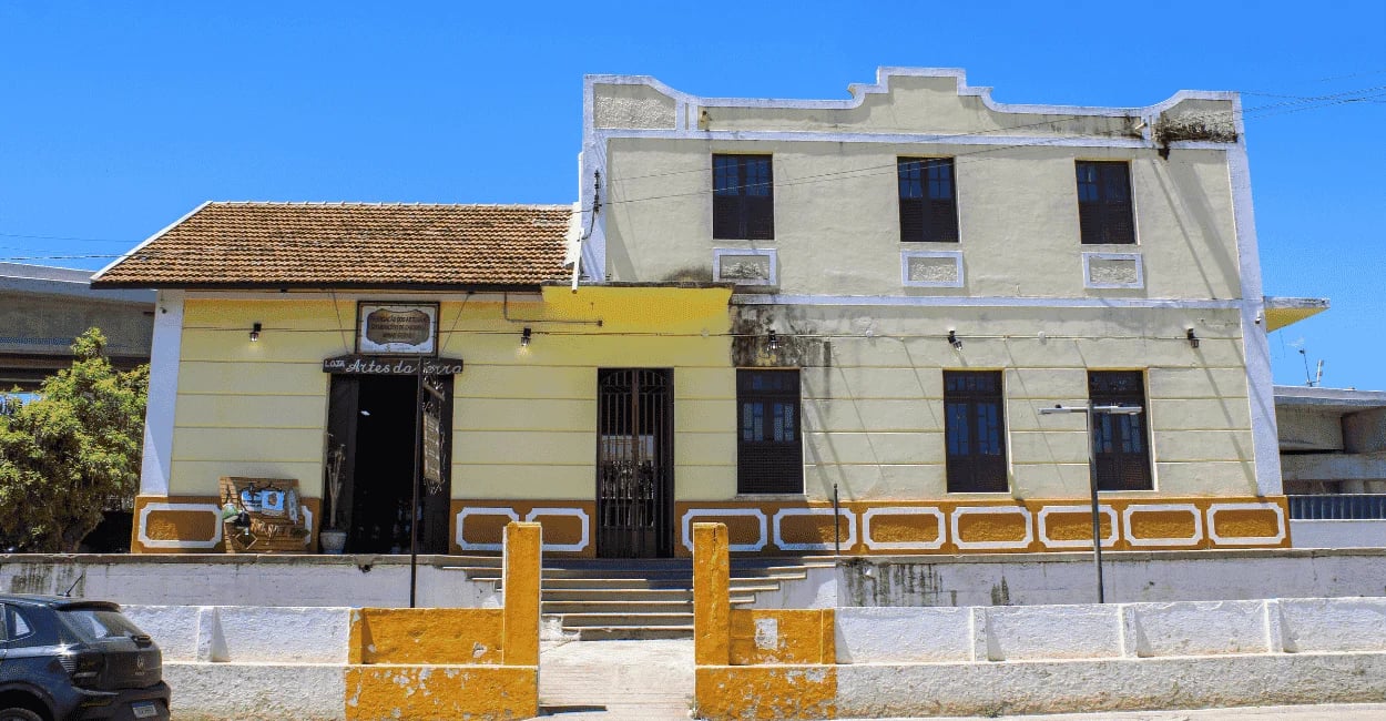 Estação ferroviaria de Carandai, com cores amarelas e detalhes branco e céu azul