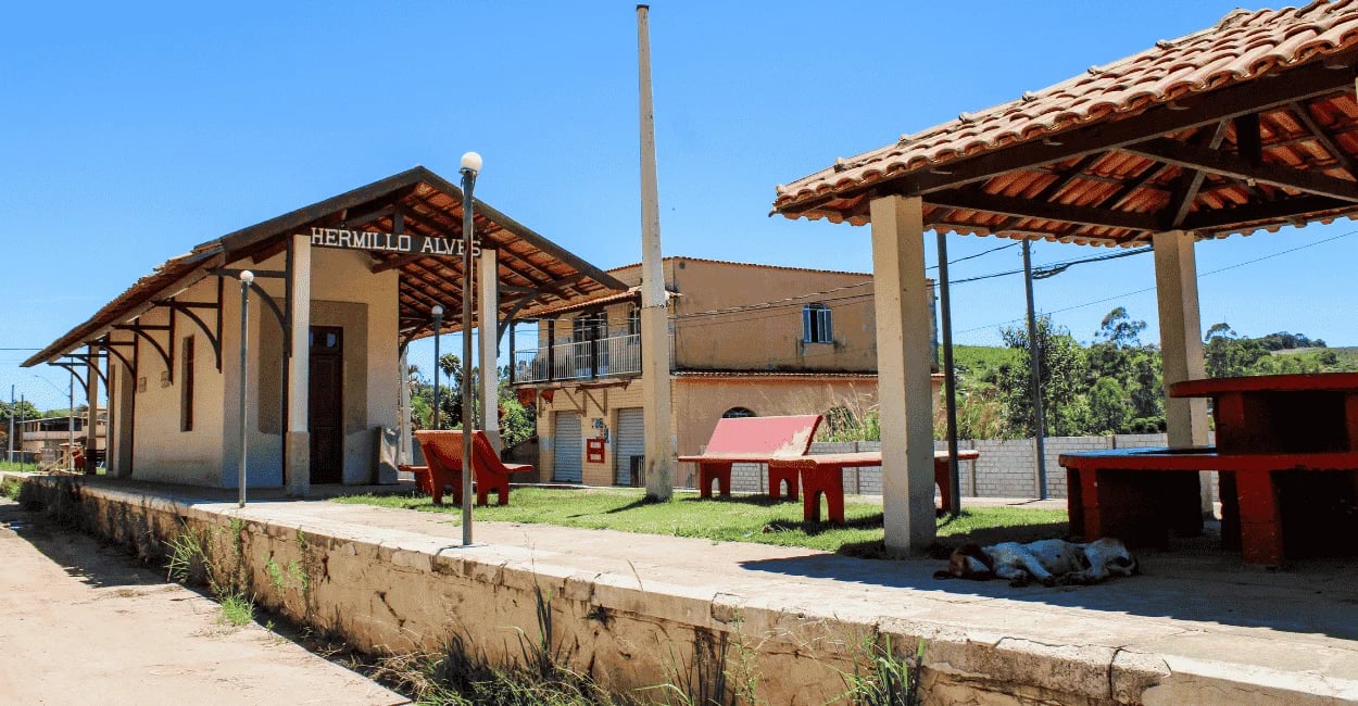 Estação ferroviária de Hermílio Alves MG com plataforma antiga, telhado colonial e bancos vermelhos