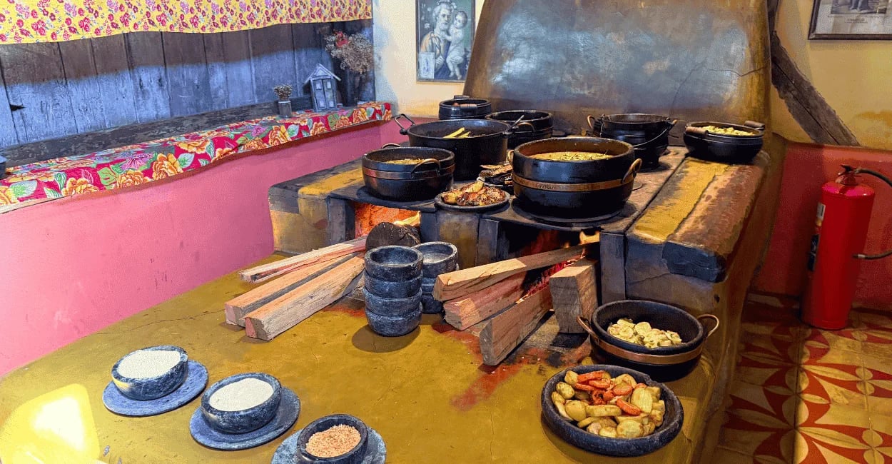 Fogão a lenha em Itatiaia, com panelas de ferro, comida mineira e ambiente rústico colorido