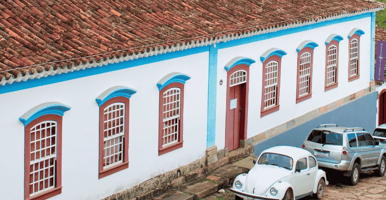 Casarão colonial em Tiradentes MG com fachada branca e azul, janelas em sequência, telhado antigo