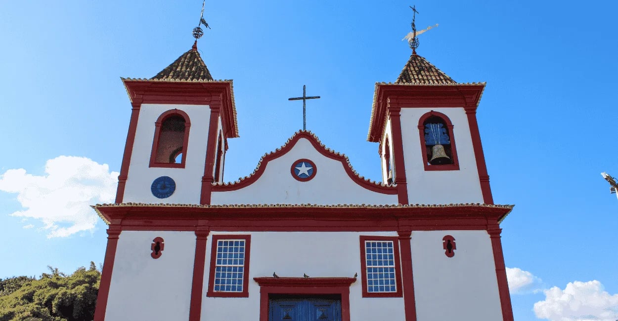 Igreja Matriz de Sabará MG com fachada branca e detalhes vermelhos sob céu azul