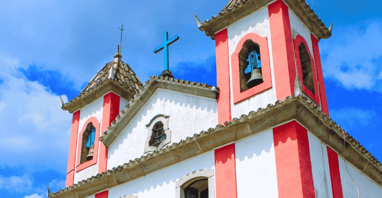 Igreja histórica branca com detalhes em rosa sob céu azul em Lavras Novas