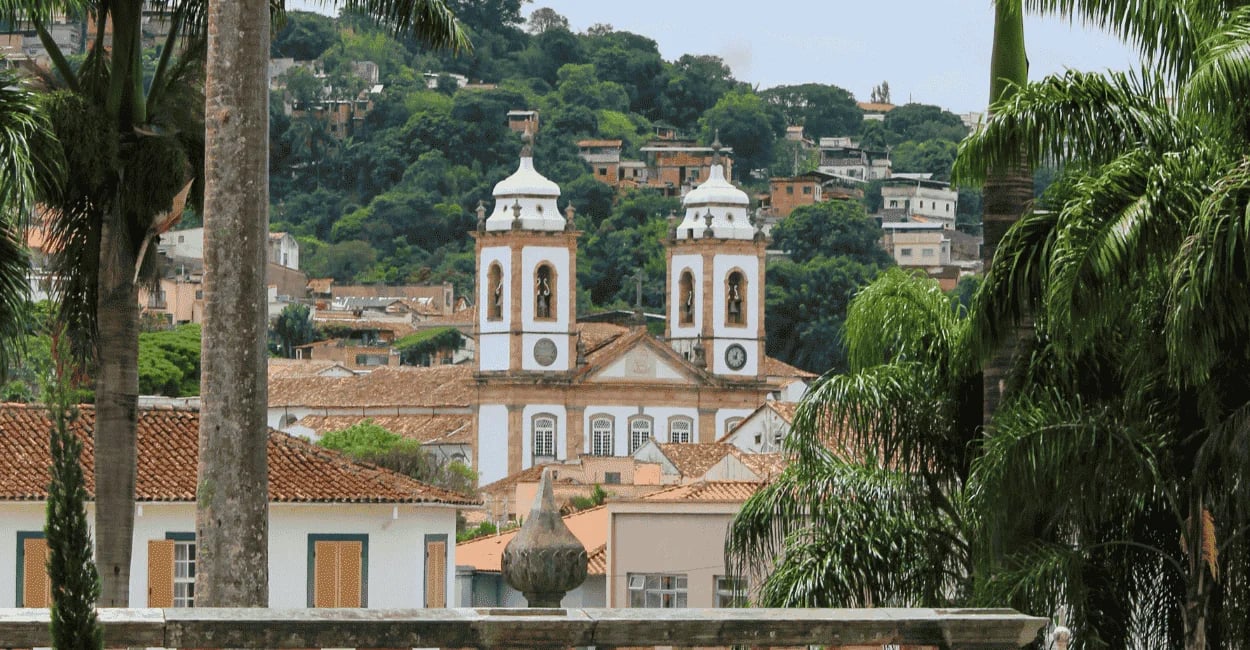 Vista de São João del Rei com igreja histórica de torres gêmeas, telhados coloniais e morro