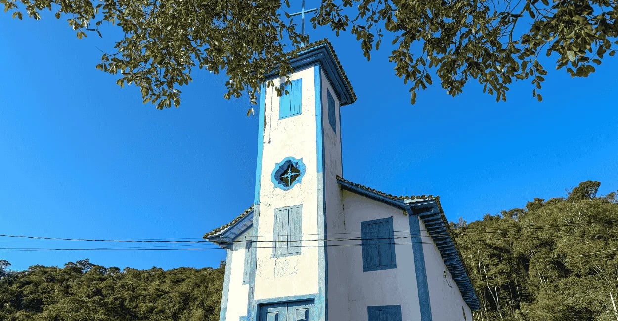 Igreja de Santo Antônio em Tapera, Minas Gerais, com fachada azul, árvores e céu aberto