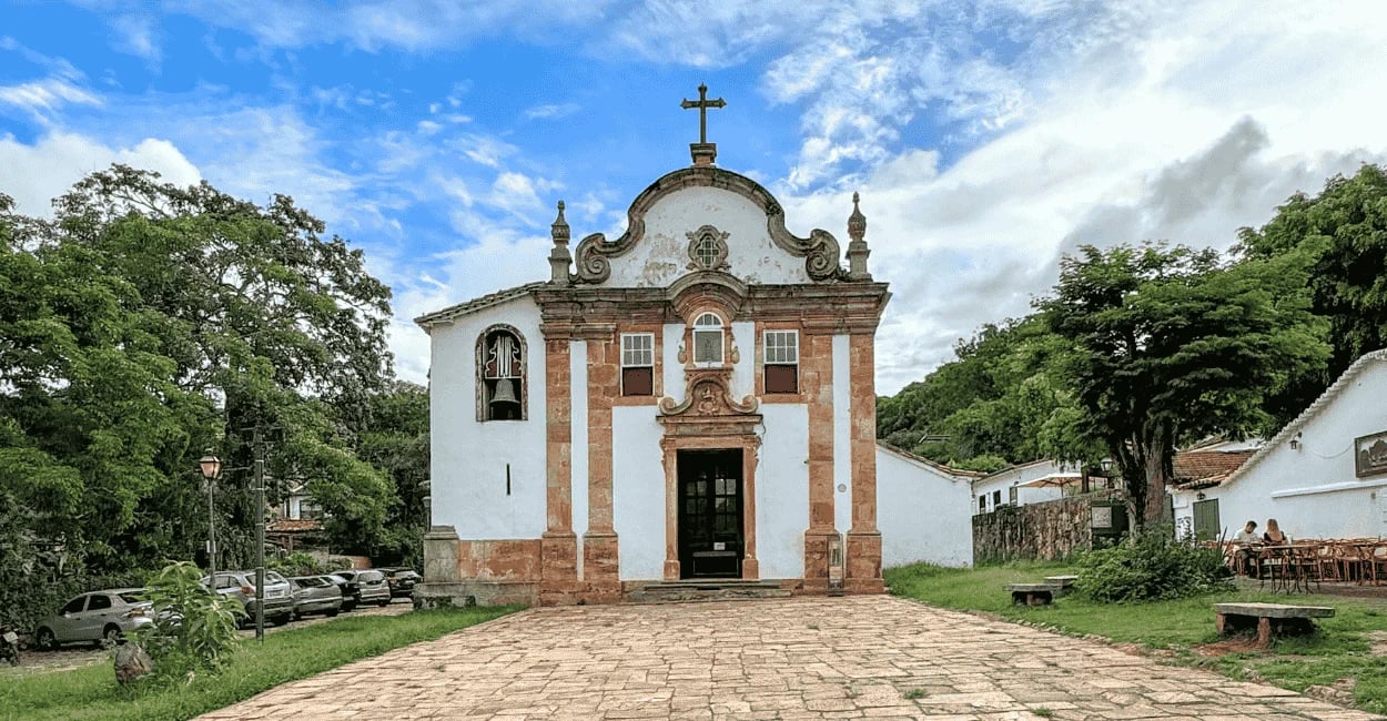 Igreja histórica com largo de pedra e vegetação em Tiradentes, Minas Gerais