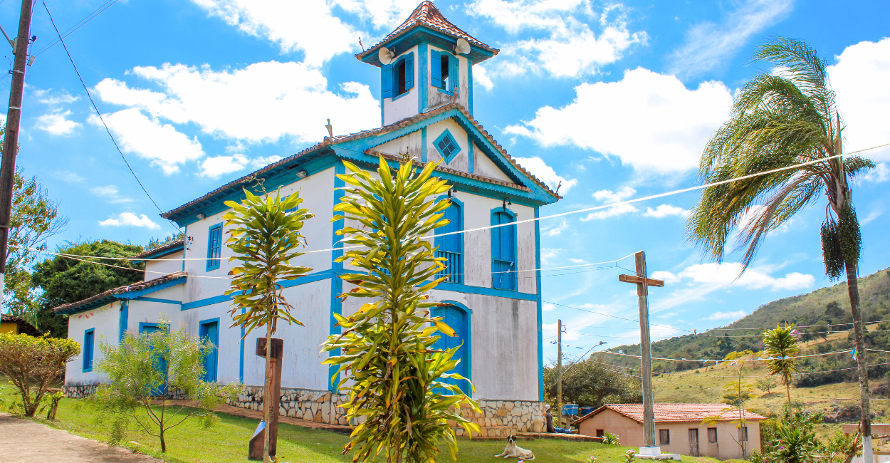 Igreja, árvores, cruz e um cachorro, no centro turistico de Três Barras, distrito de Serro MG