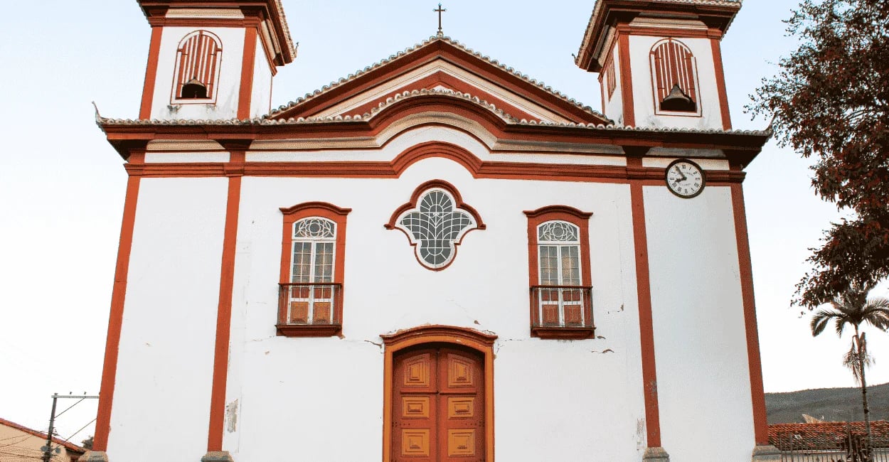 Igreja Matriz de Conceição do Mato Dentro MG com fachada branca, detalhes em vermelho e duas torres