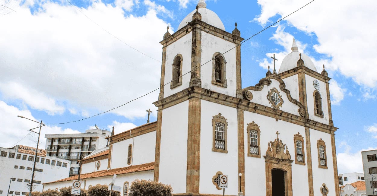 Matriz de Nossa Senhora da Assunçãoem Babacena, cor branca e detalhes em pedra sabão, céu com nuvens