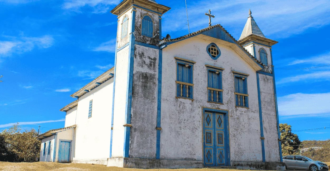Igreja Matriz de São Gonçalo do Rio das Pedras com fachada branca e azul sob céu aberto