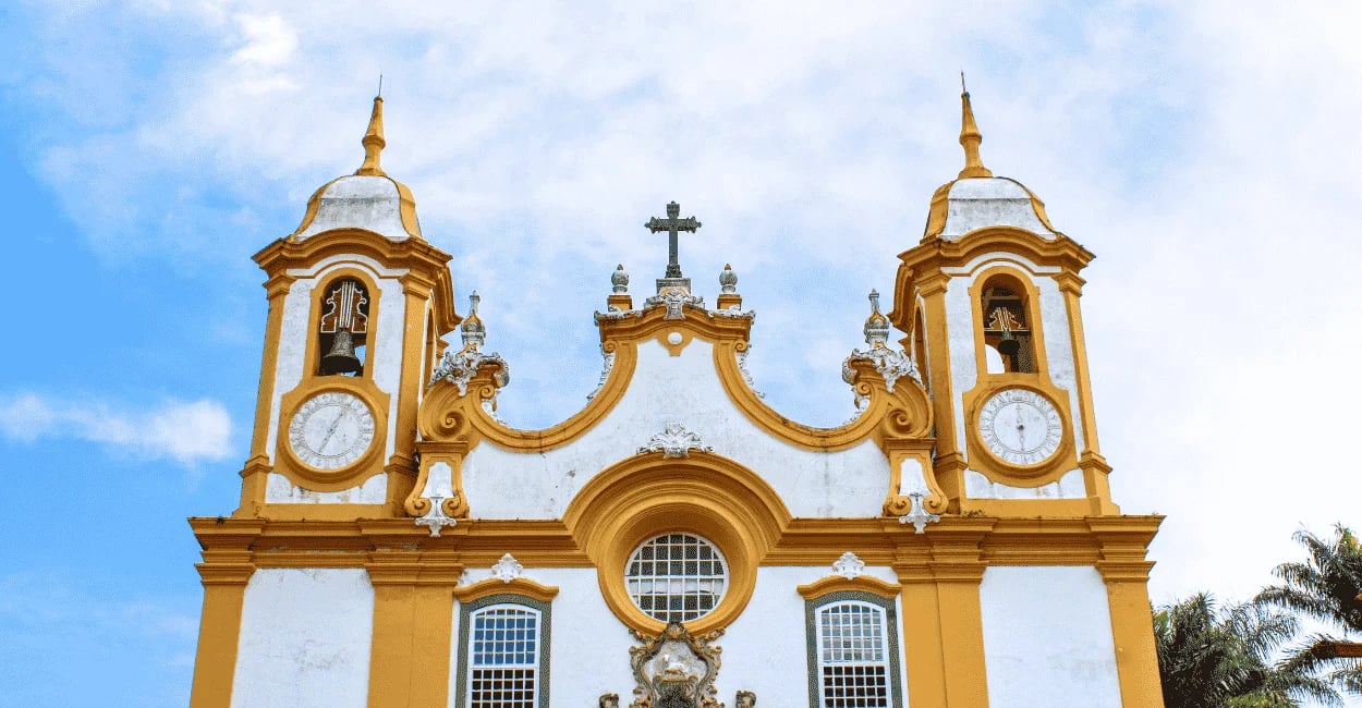 Fachada da Igreja Matriz de Tiradentes com torres barrocas, relógios e detalhes coloniais sob céu nu