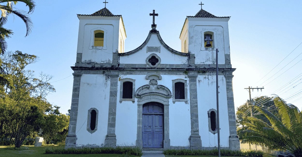 Igreja Matriz de Acuruí MG com fachada branca e torres coloniais ao céu aberto
