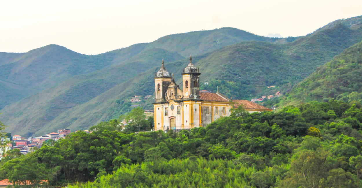 Igreja histórica e turistica envolta de vegetação e montanhas em Ouro Preto, cidade turistica de MG