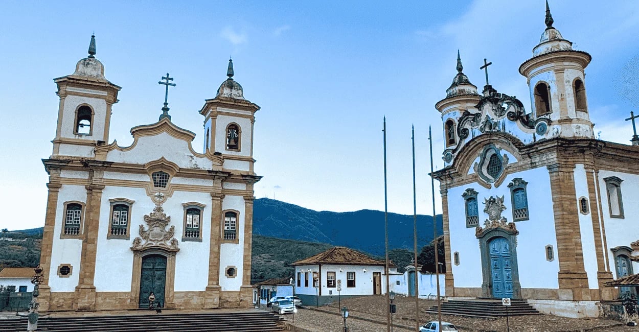 Igrejas gemeas em Mariana, Minas Gerais, fim da tarde com céu azul e motanha no fundo