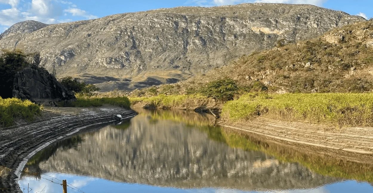 Paisagem de Lapinha da Serra com lago calmo, montanhas rochosas e reflexo da serra na água