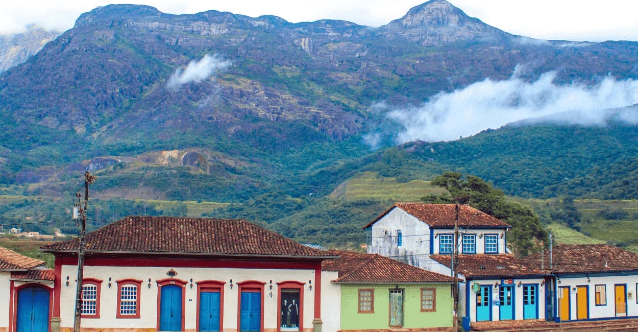 Casarões coloridos de Catas Altas MG com a Serra do Caraça e nuvens baixas ao fundo