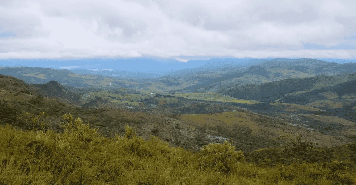 Vista panorâmica de Itambé do Mato Dentro MG com serras, vales verdes e céu carregado de nuvens