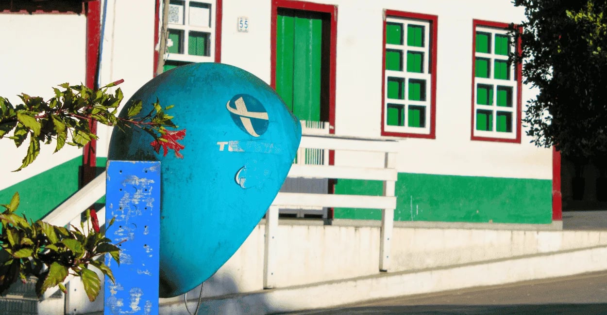 Casarão colorido em Ipoema MG com janelas verdes, detalhes vermelhos e antigo orelhão azul
