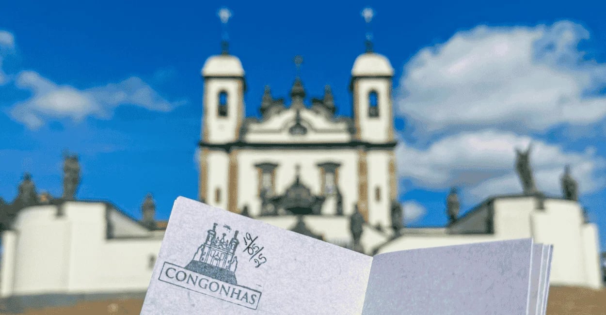 Passaporte da Estrada Real com carimbo de Congonhas diante do Santuário do Bom Jesus de Matosinhos
