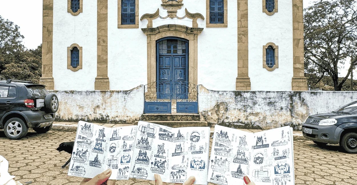 Passaporte da Estrada Real com carimbos em frente à igreja histórica de Glaura, em Ouro Preto