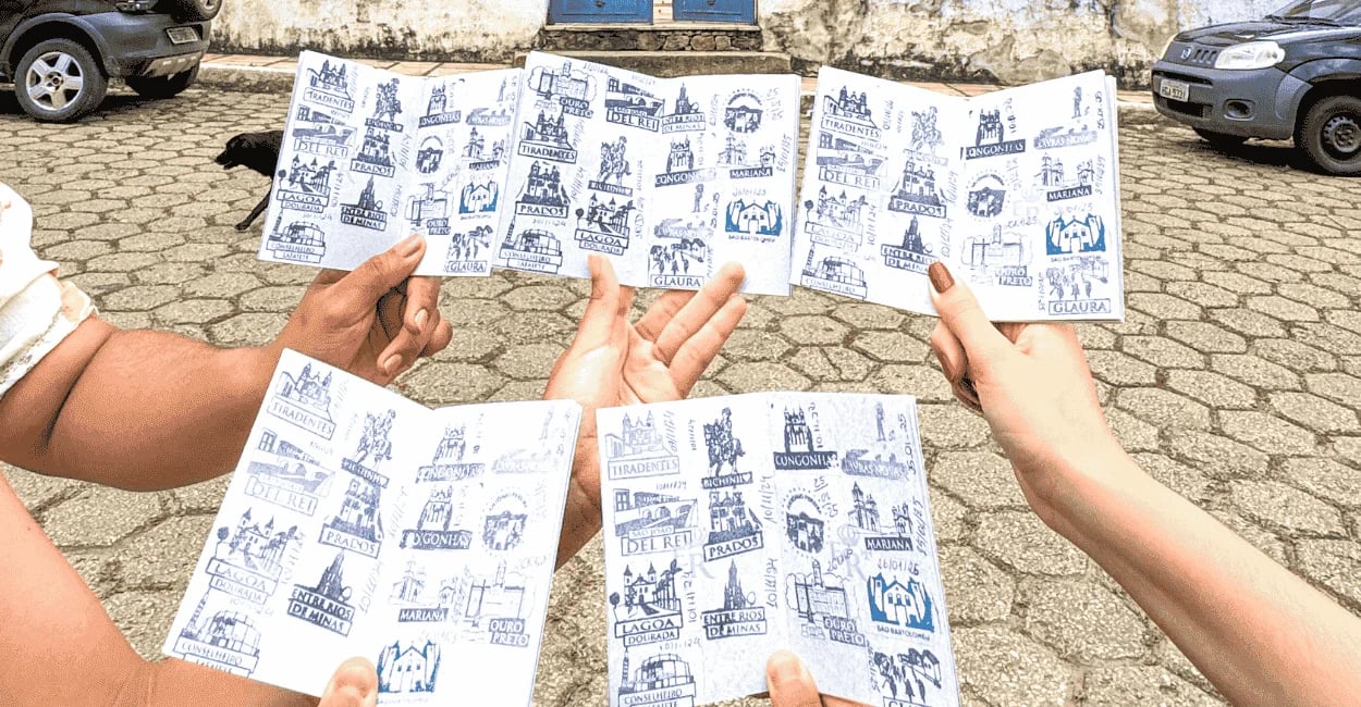 Passaportes da Estrada Real com carimbos de cidades históricas sobre rua de pedra em Minas Gerais