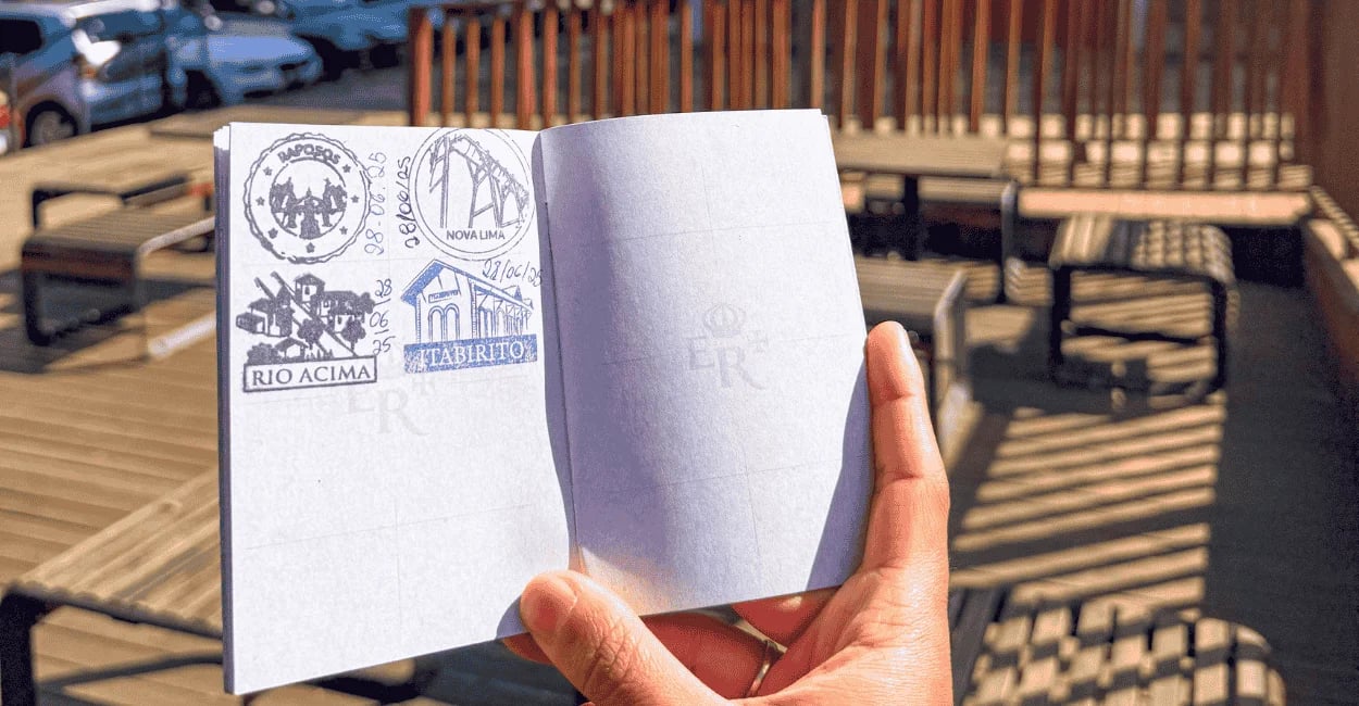 Passaporte da Estrada Real aberto exibindo carimbos de Itabirito e outras cidades sob o sol
