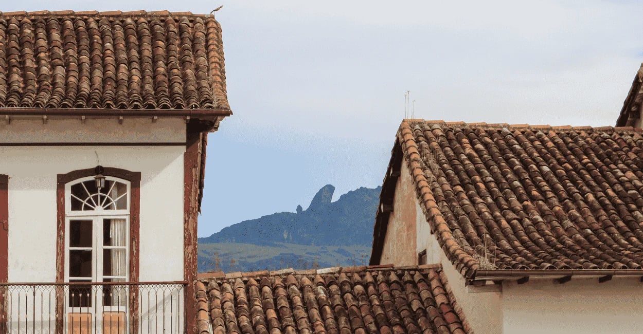 Telhados coloniais de Ouro Preto, MG, com o Pico do Itacolomi ao fundo entre casarões históricos