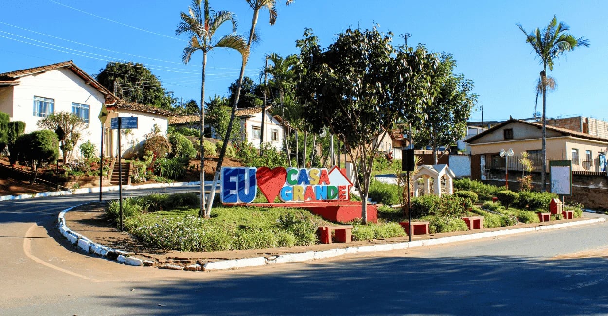 Praça de Casa Grande em Minas Gerais com letreiro colorido, jardins e casas ao redor