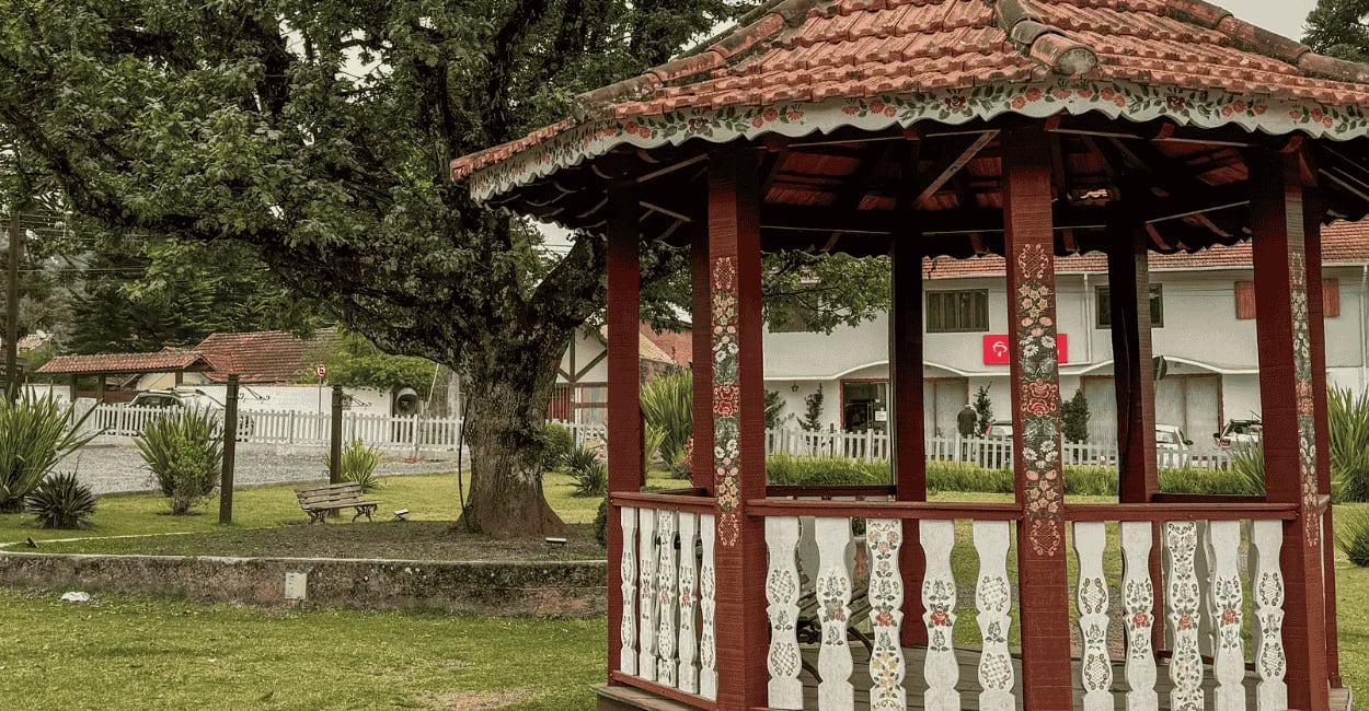 Coreto de madeira e colunas decoradas com pinturas de flores na Praça da Árvore em Monte Verde