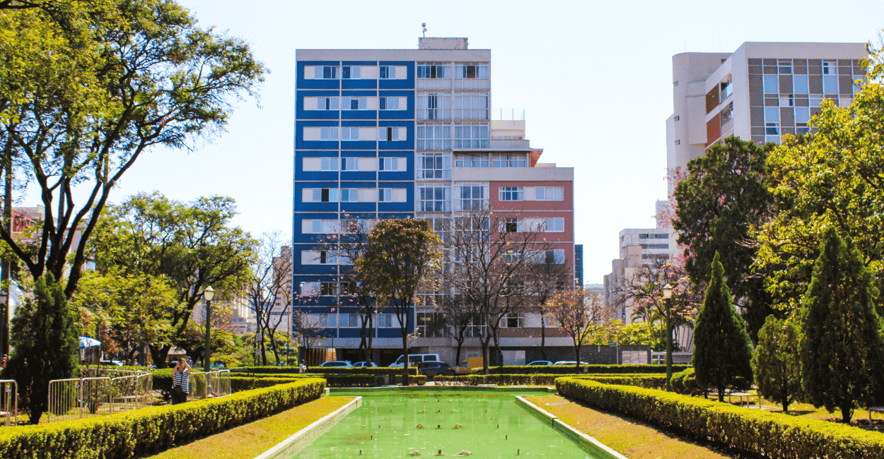 Prédios azul e rosa, água no chafariz desligado e árvores na Praça da Liberdade em BH MG