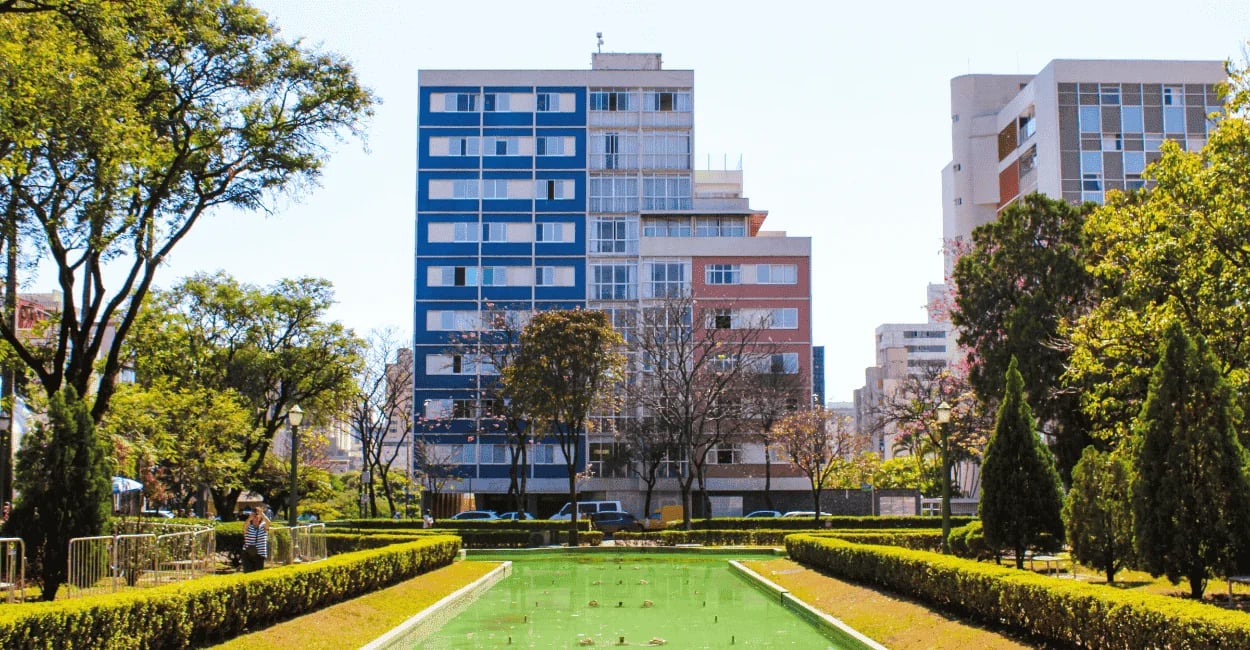 Prédios azul e rosa, água no chafariz desligado e árvores na Praça da Liberdade em BH MG